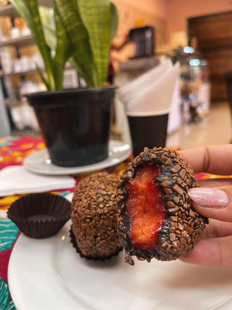 Surpresa de Morango mordida mostrando morango fresco dentro do brigadeiro com granulado — Casa do Brigadeiro