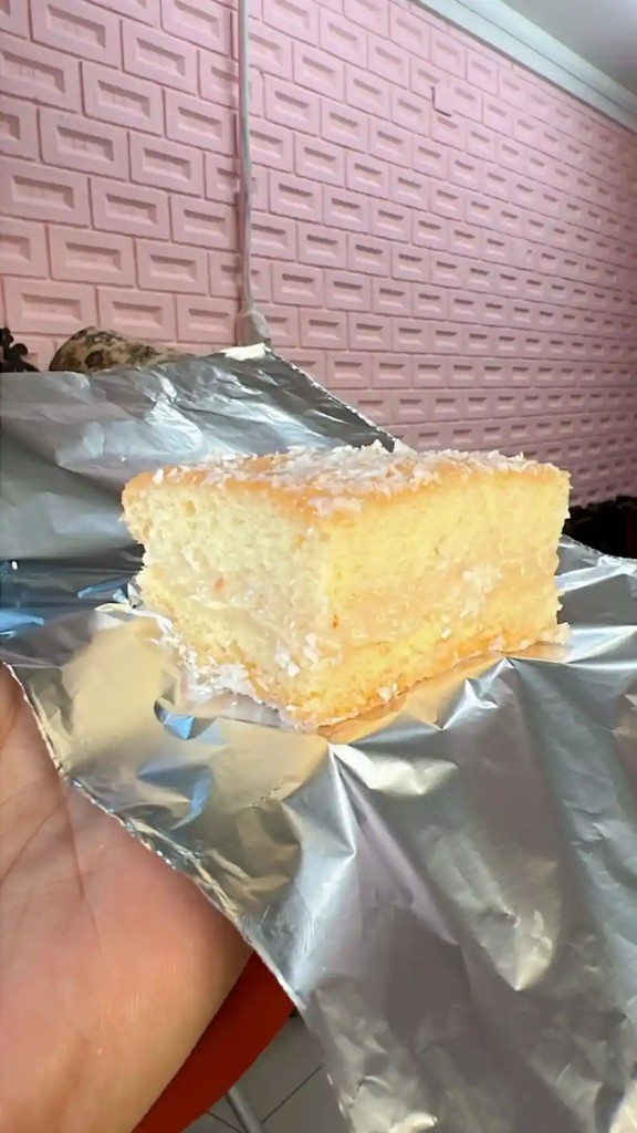 Fatia de bolo gelado com recheio cremoso e cobertura de coco ralado