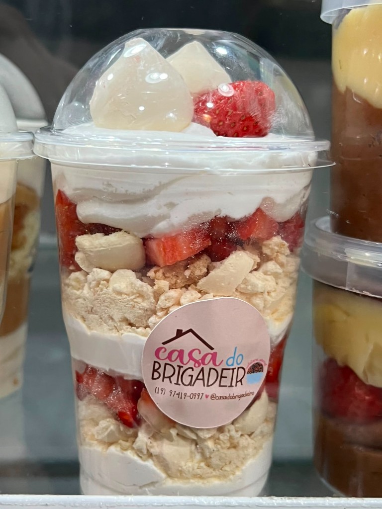 Copo da felicidade com camadas de morango, suspiro e creme na vitrine Casa do Brigadeiro